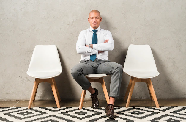 portrait-smiling-young-businessman-sitting-chair-with-his-arm-crossed
