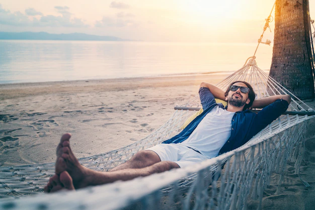 oung-handsome-latin-man-sunglasses-relaxing-hammock-beach-sunset-beach